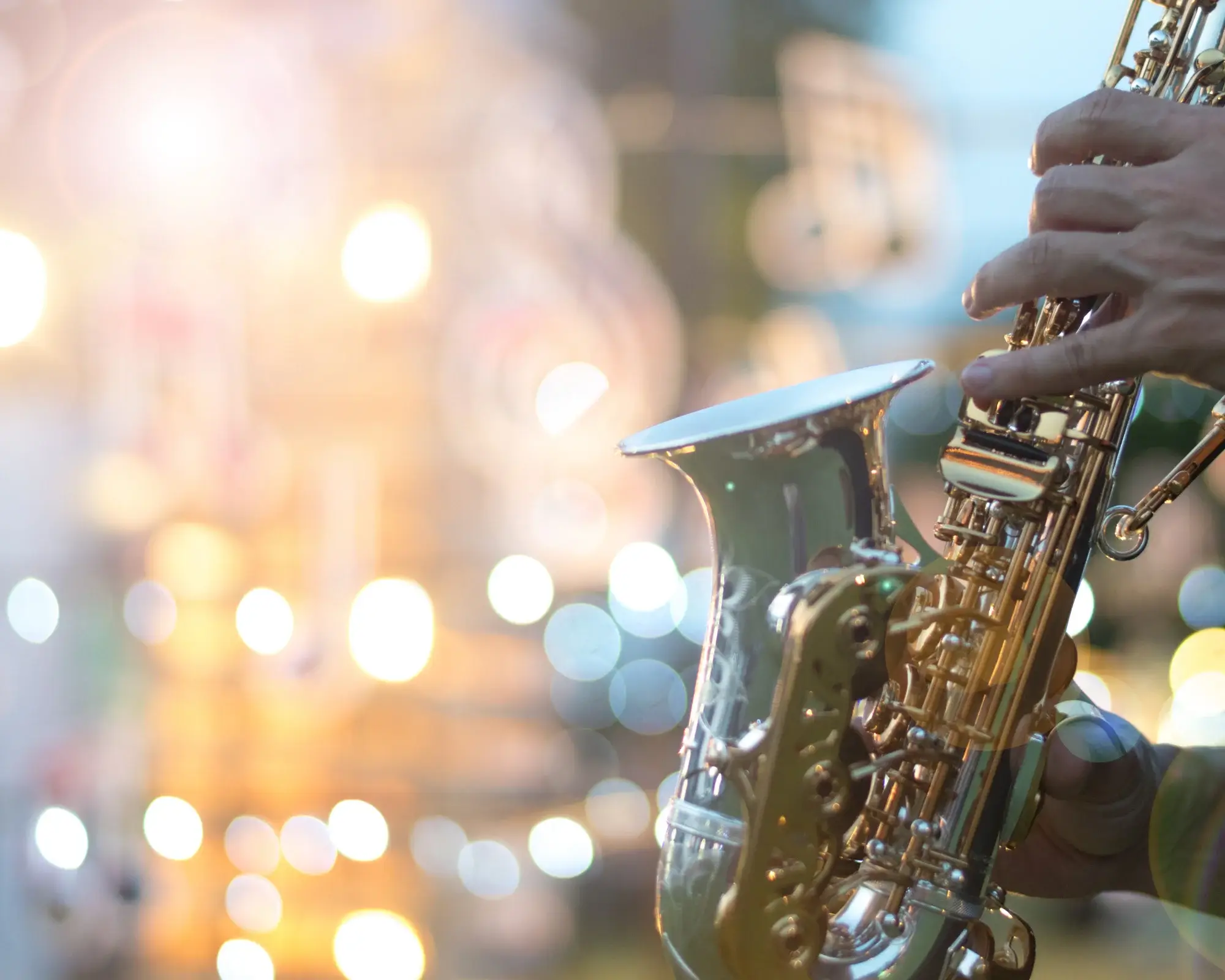A person playing the saxophone in front of lights.