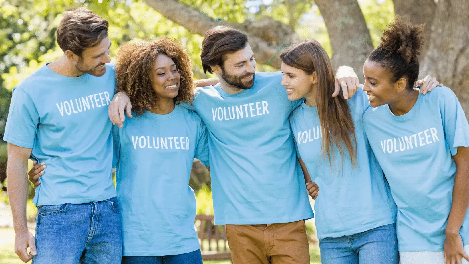 A group of people wearing blue shirts and smiling.