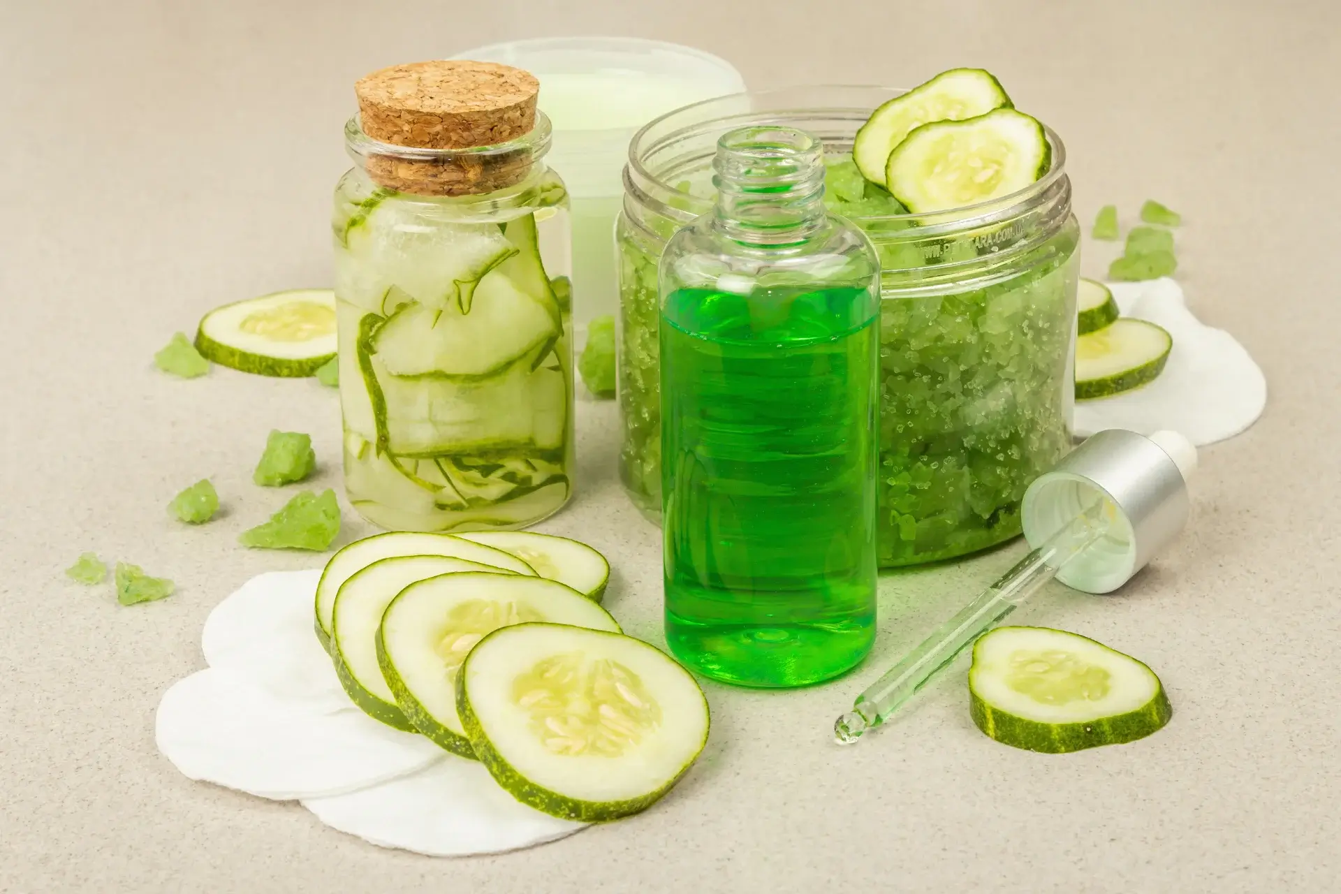 A table topped with jars of cucumber slices and green liquid.