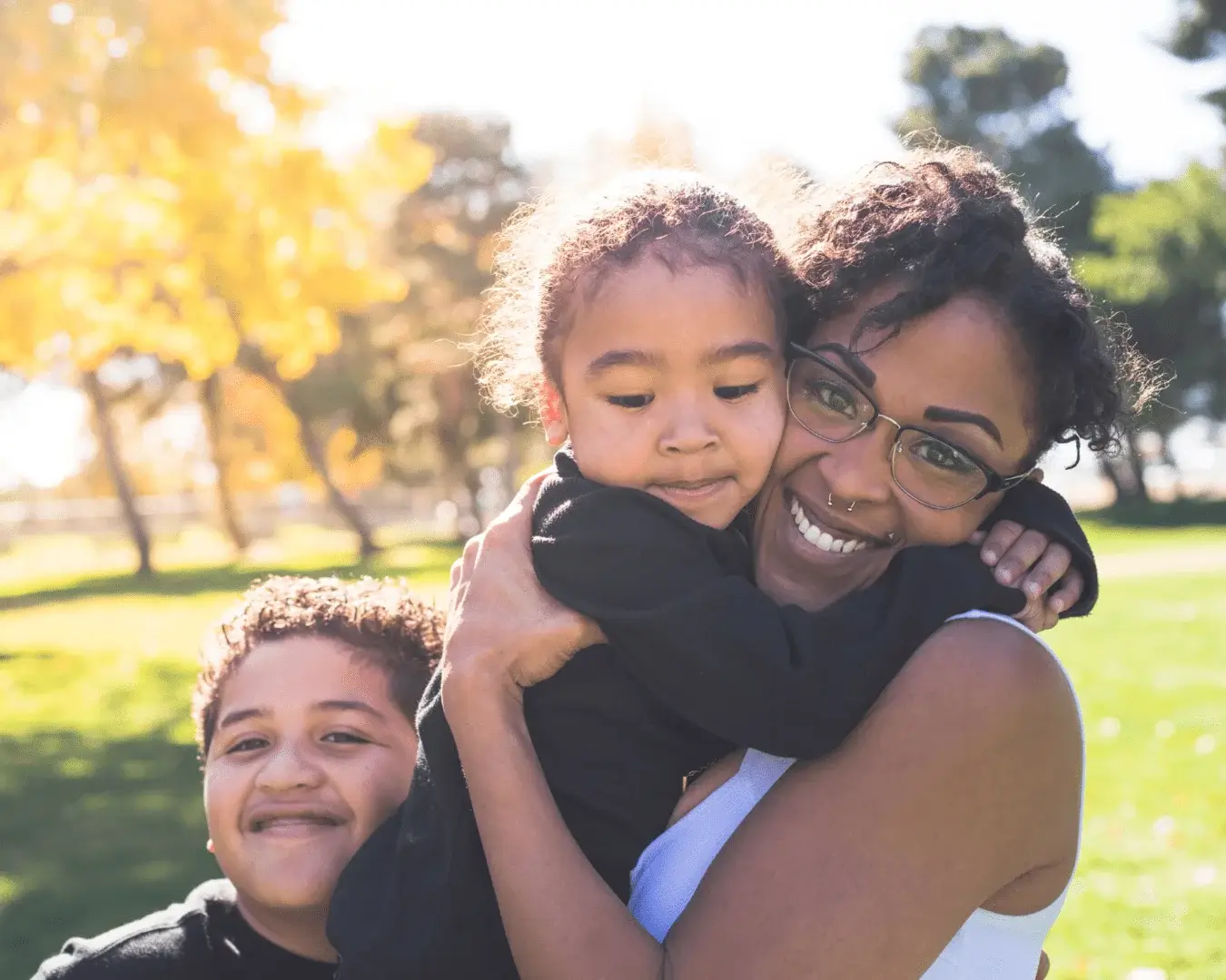 A woman holding two children in her arms.